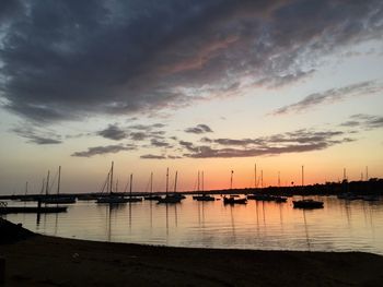 Sailboats moored in marina at sunset