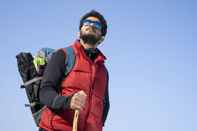 Young indian traveler boy trekking over a rocky mountain, standing on the top of the mountain.