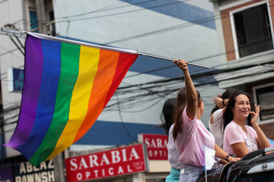 People with multi colored flags against the wall