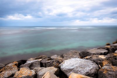 Rocks by sea against sky