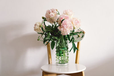 Pink peonys bouquet on a white chair in the living room.