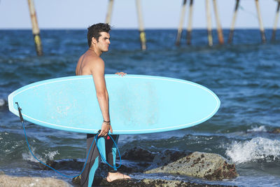 Full length of shirtless man standing in sea