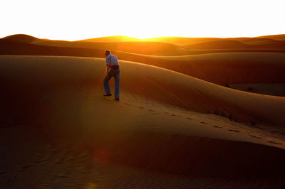 Man on sand dune in desert against sky