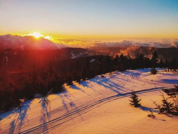 Scenic view of snow covered land against sky during sunset