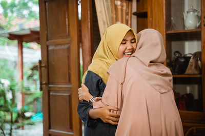 Smiling young females greeting at home