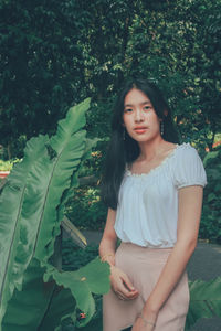 Beautiful young woman standing against plants