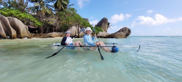 Two women in crystal kayak in sea against sky