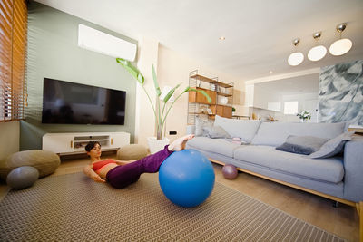 Woman exercising on fitness ball at home