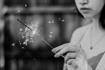 Midsection of woman holding illuminated sparkler
