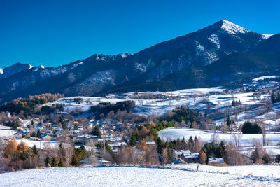 Townscape by mountains against clear blue sky