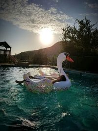 Man relaxing on duck in swimming pool against sky