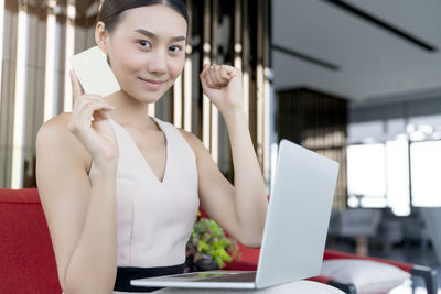 Portrait of a smiling young woman using phone