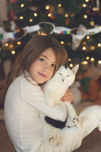 Portrait of happy girl holding cat at home