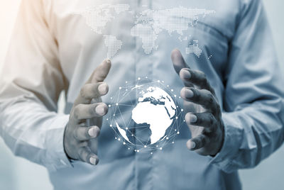 Digital composite image of businessman holding globe