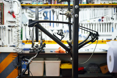 Frame of modern bike hanging on rack against workbench and wall with tools in repair workshop