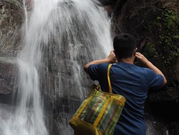 Rear view of woman standing by waterfall