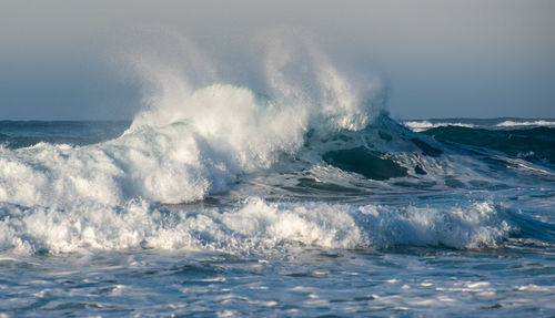 Waves splashing in sea against sky