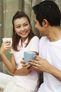 Couple talking while having coffee against wall