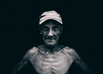 Portrait of shirtless man against black background