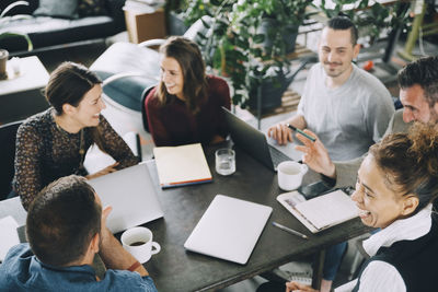 High angle view of happy business people sitting at table in creative office