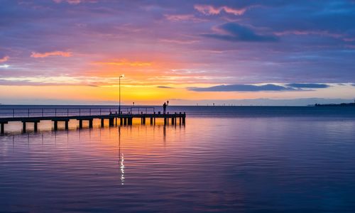 Pier on sea against sky during sunset