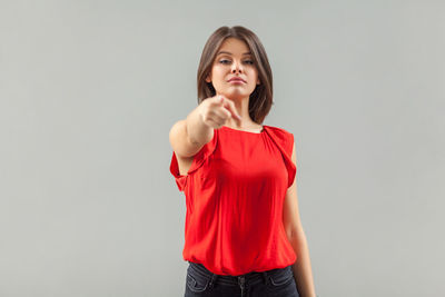 Portrait of young woman standing against white background