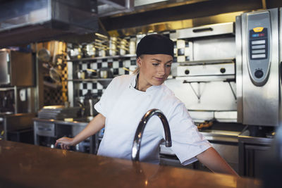 Young female chef working in kitchen at restaurant