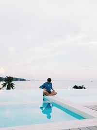 Rear view of man sitting in swimming pool