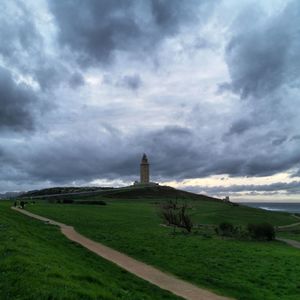 View of tower on field against cloudy sky