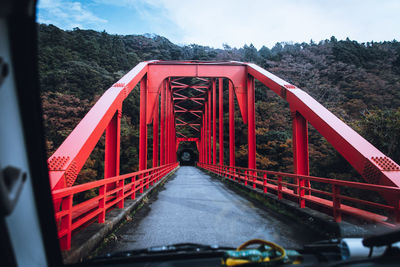 Driving car at red bridge against sky in japan