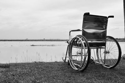 Wheelchair on field against lake