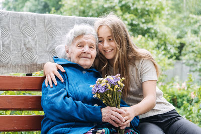 Volunteer girl and senior elderly woman with gift, flowers bouquet and basket of groceries