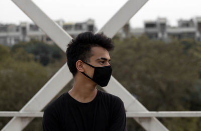 Portrait of young man standing against railing