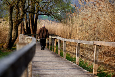 Rear view of man walking on footbridge