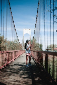 Full length of young woman standing on footbridge