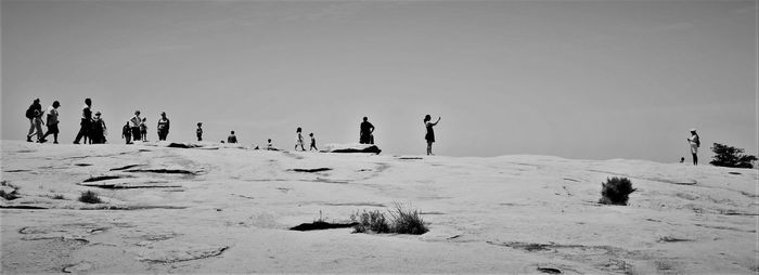 People on snow covered land against sky