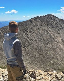 Rear view of boy standing on landscape against sky