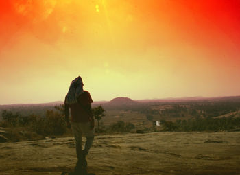 Rear view of man and woman walking on landscape against sky