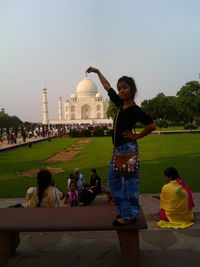 Woman with arms outstretched against sky in city