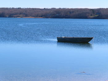 Boat moored on lake against blue sky