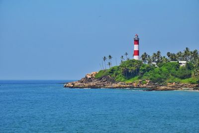 Lighthouse by sea against sky