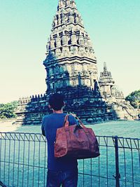 Rear view of man standing outside temple against clear sky