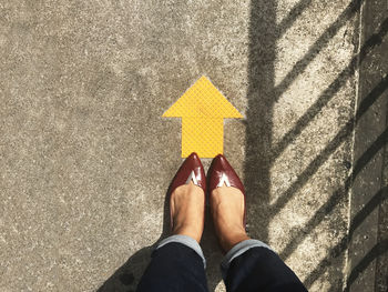 Low section of woman standing by arrow symbol on street