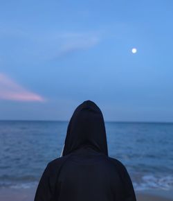 Rear view of man on sea shore against sky