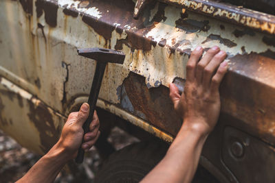 Hand holding a pickup truck hammer rusty peeling paint tires old car wheels vintage