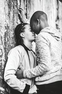 Couple romancing while standing against wall