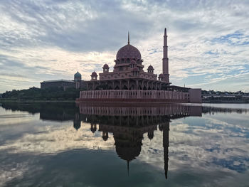 Reflection of temple in lake against cloudy sky