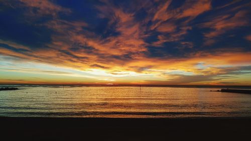 Scenic view of sea against dramatic sky during sunset