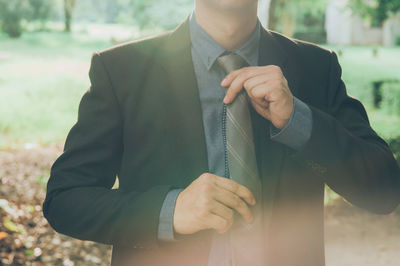 Midsection of man holding camera while standing outdoors