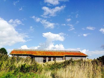 Houses on field against cloudy sky